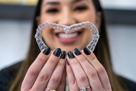 A woman showing Invisalign clear braces.