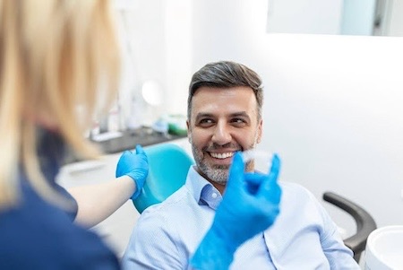 A smiling middle-aged man getting his Invisalign clear aligners at the dentist's office.
