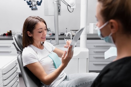 A beautiful female patient marking documents while sitting on a chair at the dentist's office.