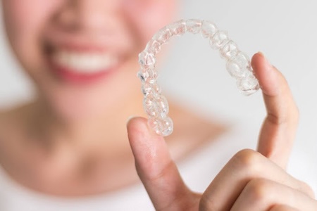 A beautiful smiling woman showing Invisalign clear aligners.