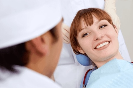 A beautiful woman with a charismatic smile is getting her teeth examined by a dentist.