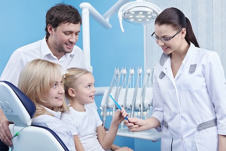 A female dentist giving an adorable little girl a toothbrush.