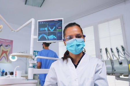 A dentist at her dental office getting ready for teeth wisdom teeth removal surgery.