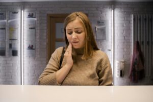 Woman experiencing toothache at dental clinic reception