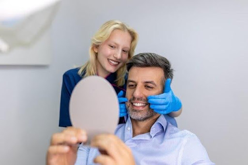Patient smiling while viewing results in a mirror during a dental treatment consultation for full mouth reconstruction.