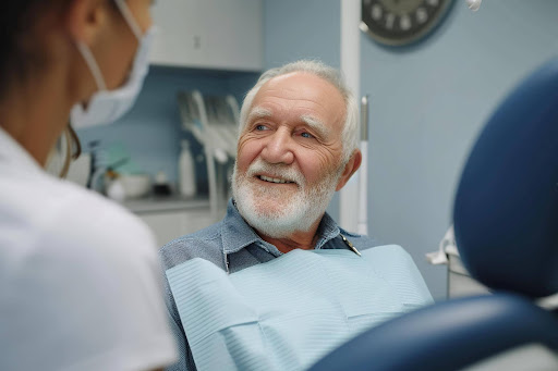 Senior male patient smiling during a dental reconstruction cost consultation with a dentist for full mouth reconstruction near you.